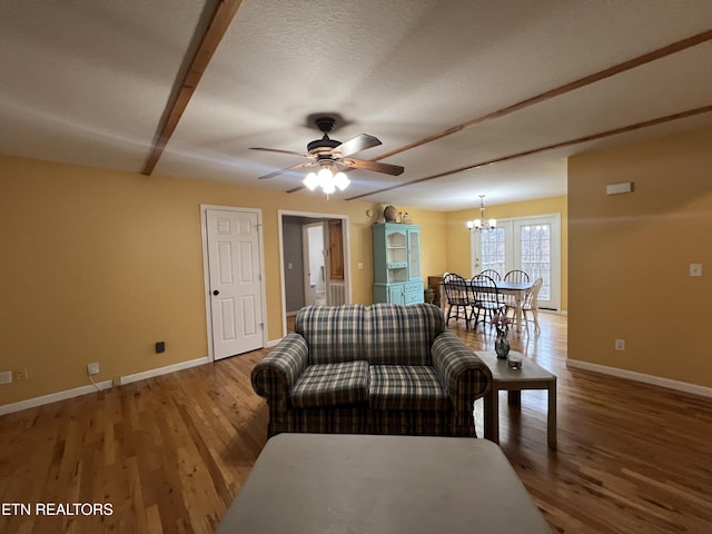 living room featuring ceiling fan with notable chandelier, wood-type flooring, and a textured ceiling