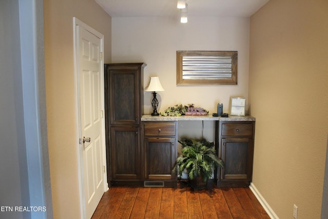 bar with dark brown cabinets and dark hardwood / wood-style flooring