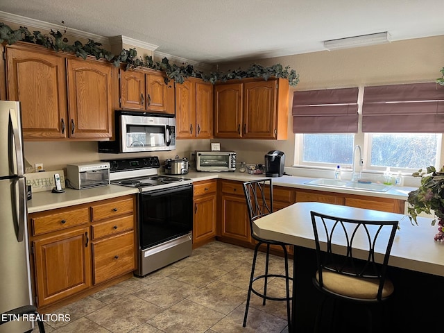 kitchen with crown molding, appliances with stainless steel finishes, sink, and a textured ceiling