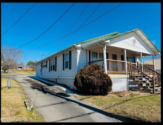 view of side of property featuring a porch and a lawn