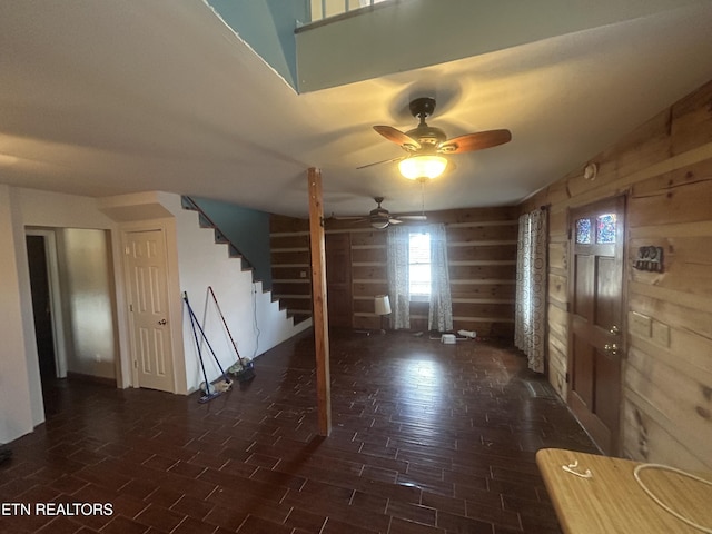 entrance foyer with ceiling fan and wood walls