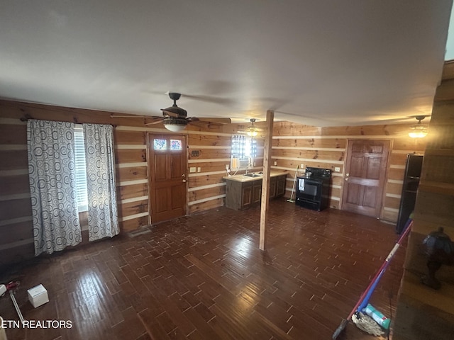 unfurnished living room featuring ceiling fan, dark hardwood / wood-style flooring, and wood walls