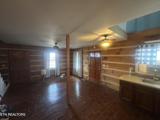 interior space featuring sink, wooden walls, dark hardwood / wood-style floors, and ceiling fan