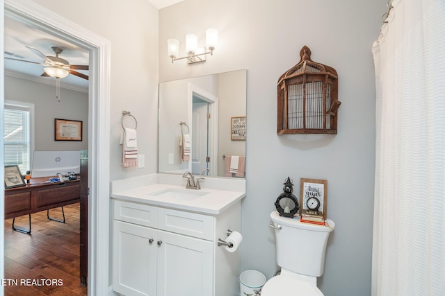 bathroom featuring toilet, ornamental molding, ceiling fan, vanity, and wood finished floors