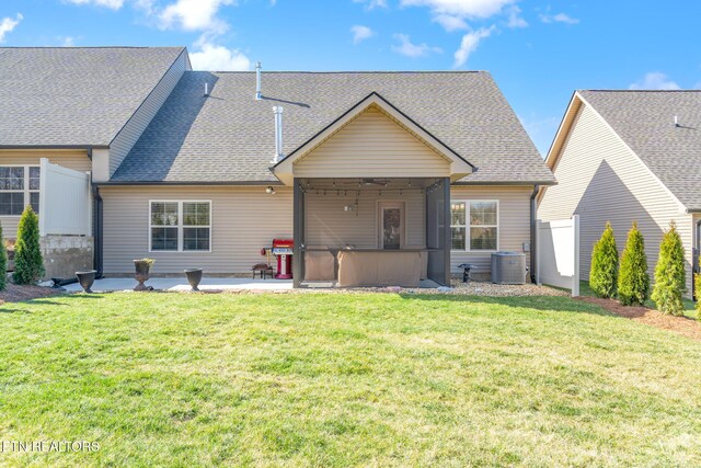 back of property with roof with shingles, a patio, a lawn, central AC unit, and fence