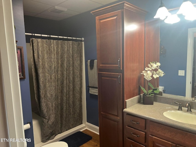 bathroom featuring vanity, hardwood / wood-style floors, toilet, and a drop ceiling