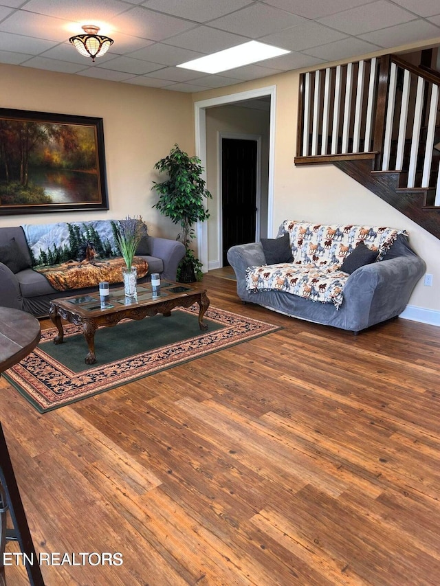 living room with wood-type flooring and a drop ceiling