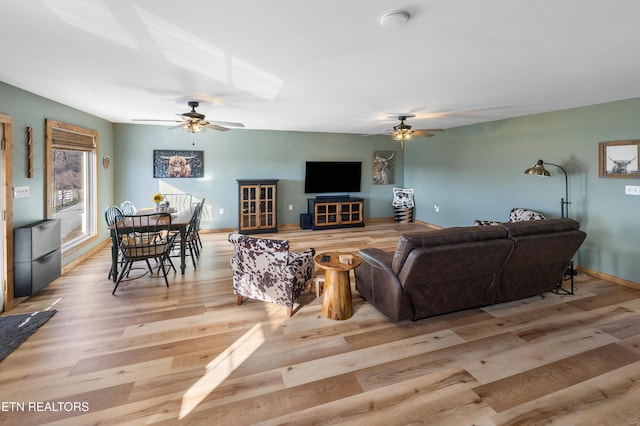 living room with a fireplace, ceiling fan, and light wood-type flooring