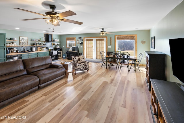 living room featuring light wood-type flooring, sink, and ceiling fan