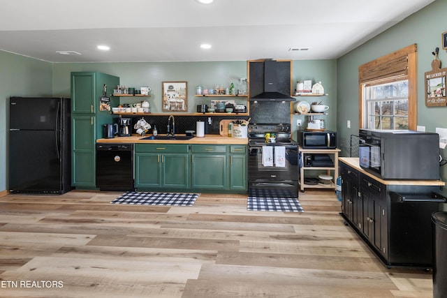 kitchen with sink, black appliances, green cabinetry, and wall chimney exhaust hood