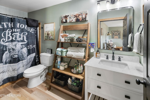 bathroom featuring wood-type flooring, vanity, toilet, and walk in shower