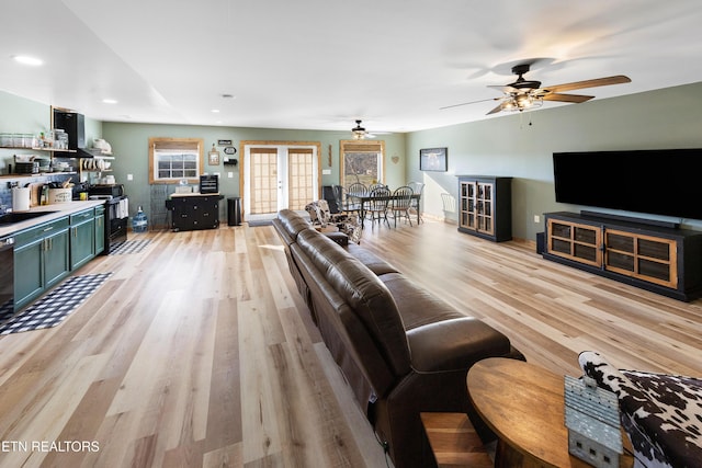 living room featuring light wood-type flooring, french doors, and ceiling fan