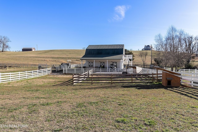 exterior space featuring a rural view, an outdoor structure, and a lawn