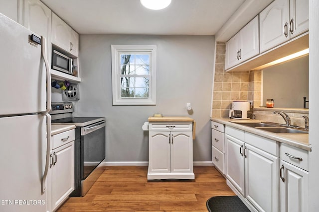 kitchen with sink, stainless steel appliances, light hardwood / wood-style floors, white cabinets, and decorative backsplash