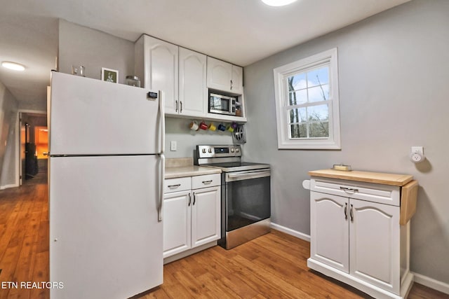 kitchen with white cabinetry, light hardwood / wood-style floors, wooden counters, and appliances with stainless steel finishes