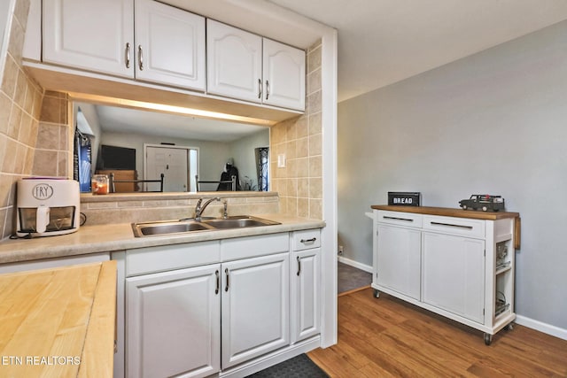 kitchen with white cabinetry, sink, decorative backsplash, and light wood-type flooring