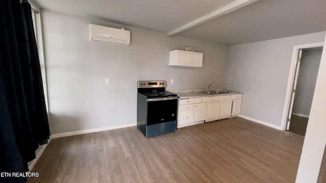 kitchen featuring a wall mounted air conditioner, wood-type flooring, sink, white cabinets, and stainless steel range with electric cooktop