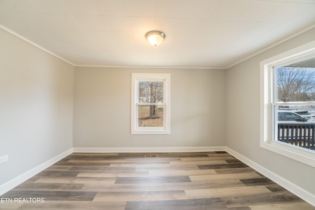 unfurnished room with hardwood / wood-style flooring, crown molding, and a wealth of natural light