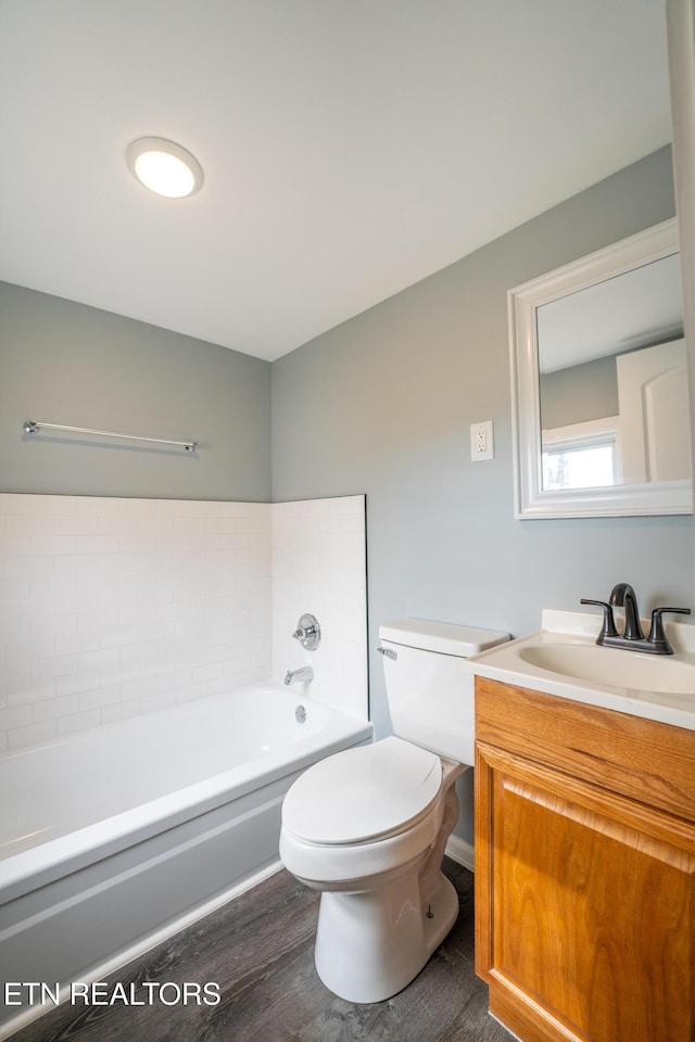 bathroom with toilet, hardwood / wood-style floors, vanity, and a tub to relax in