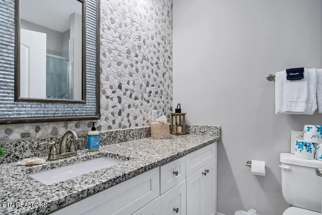 bathroom with vanity, an enclosed shower, tasteful backsplash, and toilet