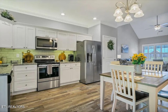 kitchen featuring pendant lighting, appliances with stainless steel finishes, white cabinetry, backsplash, and light stone countertops