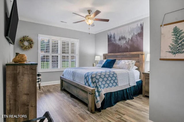 bedroom featuring hardwood / wood-style floors, ornamental molding, and ceiling fan