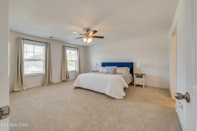 carpeted bedroom with ceiling fan and a textured ceiling