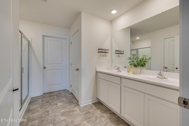 bathroom featuring a shower with door and vanity