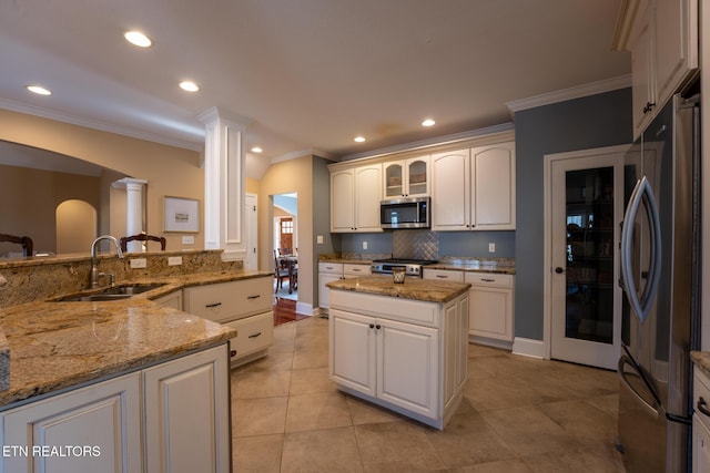 kitchen with light stone counters, stainless steel appliances, sink, and a kitchen island