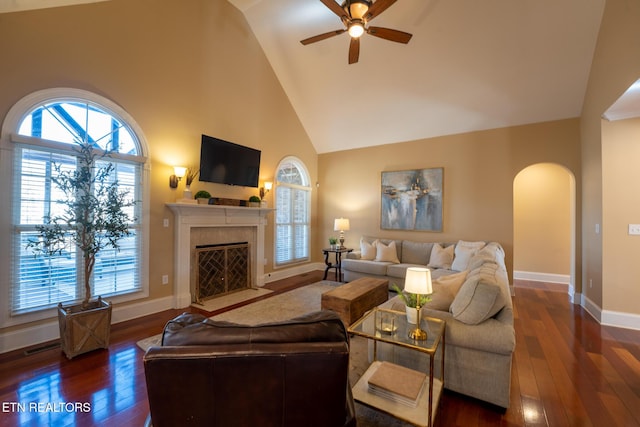 living room with a premium fireplace, dark wood-type flooring, ceiling fan, and high vaulted ceiling