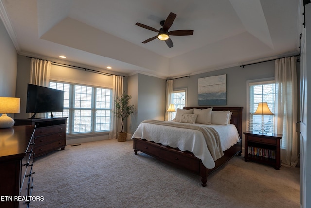 bedroom with crown molding, light colored carpet, a tray ceiling, and ceiling fan