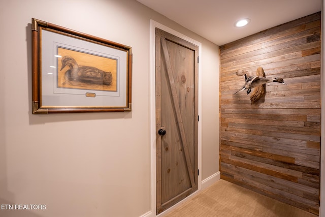 interior space with light colored carpet and wood walls