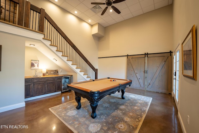 playroom with a high ceiling, a paneled ceiling, wine cooler, and ceiling fan