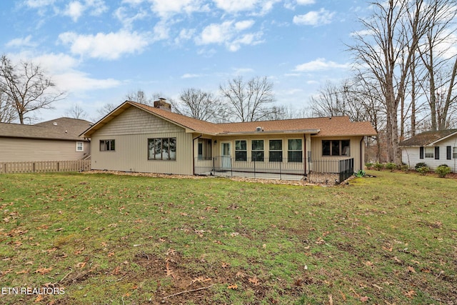 back of house with a yard, a chimney, and fence