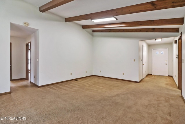 spare room featuring beam ceiling, light carpet, and baseboards