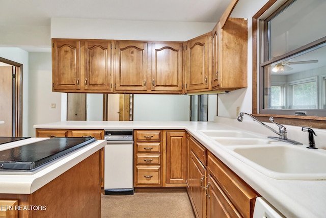 kitchen featuring a peninsula, brown cabinetry, light countertops, and a sink