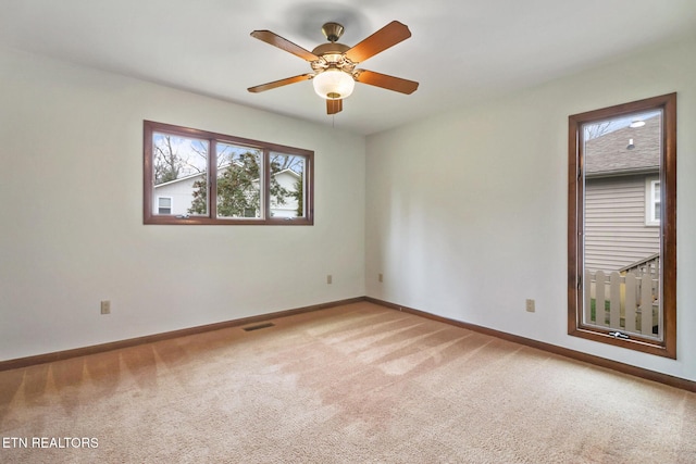 carpeted empty room with baseboards, visible vents, and ceiling fan