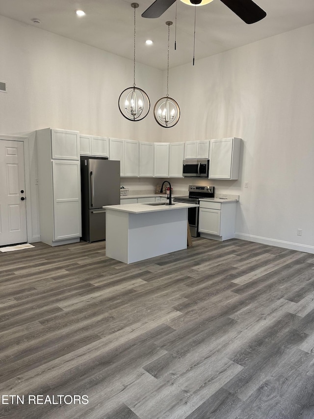 kitchen featuring sink, decorative light fixtures, a towering ceiling, stainless steel appliances, and white cabinets