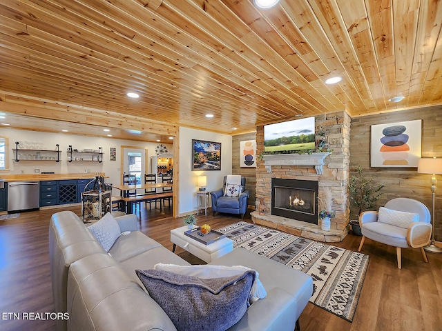 living room with wooden walls, a stone fireplace, recessed lighting, wooden ceiling, and wood finished floors