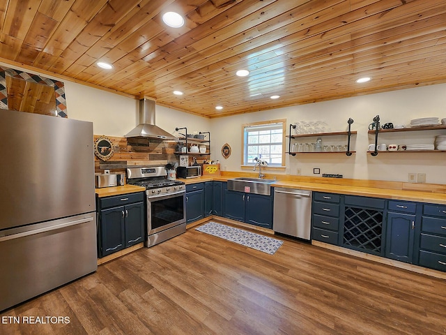 kitchen featuring open shelves, butcher block counters, appliances with stainless steel finishes, wall chimney exhaust hood, and a sink