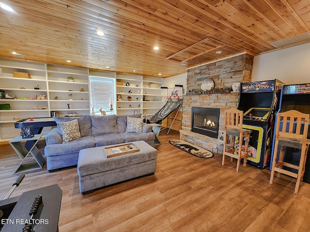 living area with a stone fireplace, wood finished floors, built in features, and wood ceiling