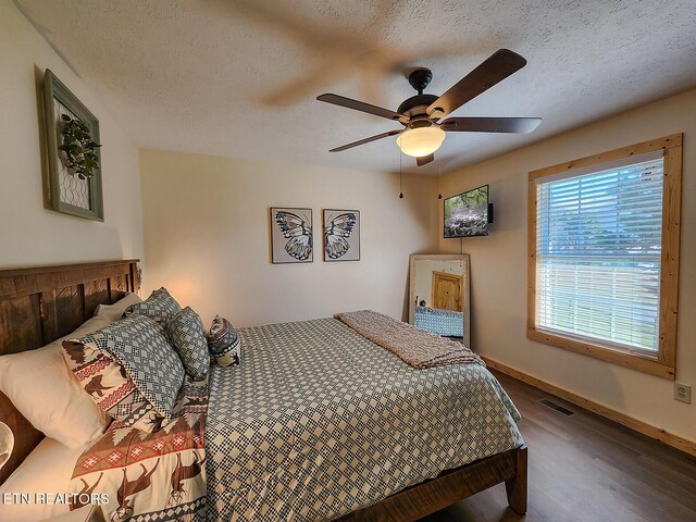 bedroom featuring visible vents, baseboards, wood finished floors, a textured ceiling, and a ceiling fan