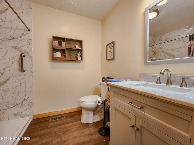 bathroom featuring visible vents, toilet, a textured ceiling, wood finished floors, and a marble finish shower