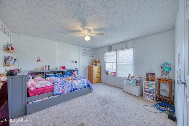 carpeted bedroom featuring ceiling fan and a textured ceiling