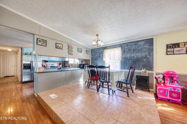 dining room featuring lofted ceiling, crown molding, light hardwood / wood-style flooring, a notable chandelier, and a textured ceiling