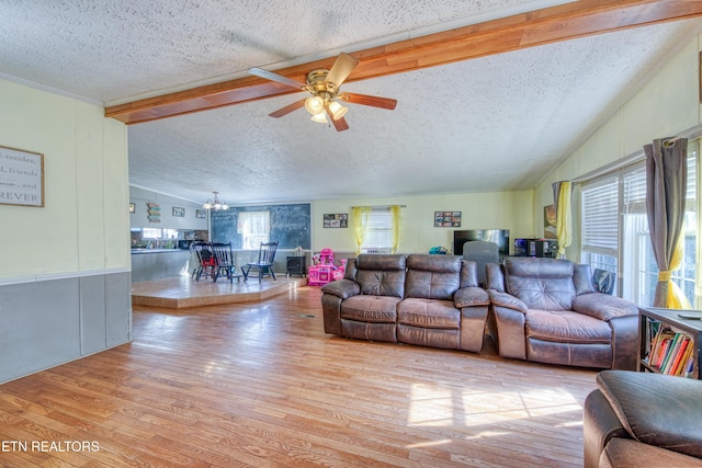 living room with ceiling fan with notable chandelier, light hardwood / wood-style floors, a textured ceiling, and lofted ceiling with beams