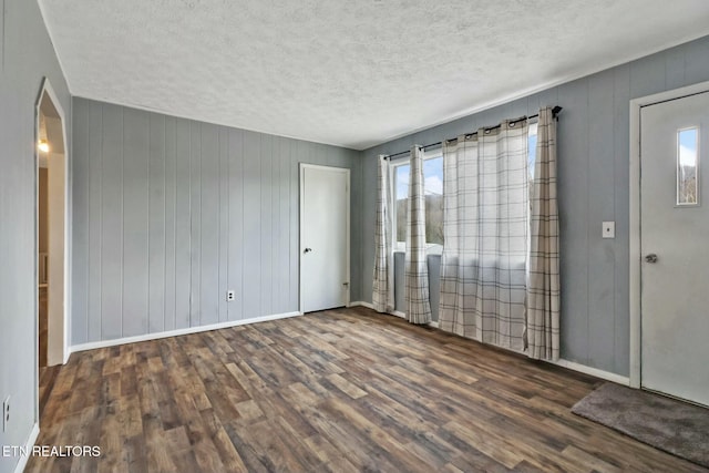 empty room with dark hardwood / wood-style floors and a textured ceiling