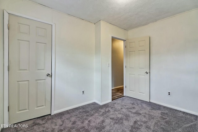 unfurnished bedroom with dark carpet and a textured ceiling