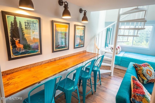 bar with light wood finished floors and hanging light fixtures