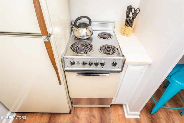 details featuring white cabinets, light countertops, wood finished floors, and white appliances